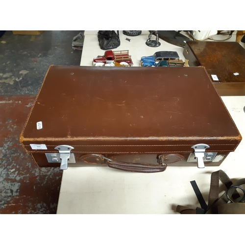 335 - A vintage brown cow hide leather suitcase with various travel stickers and chrome plated locks