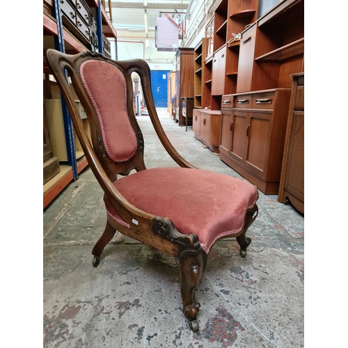 479 - A Victorian mahogany ladies parlour chair on scrolled supports and castors with pink upholstery