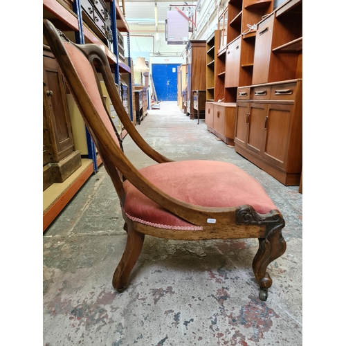 479 - A Victorian mahogany ladies parlour chair on scrolled supports and castors with pink upholstery