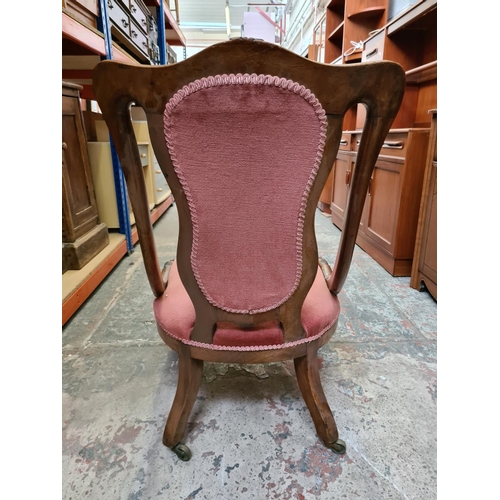 479 - A Victorian mahogany ladies parlour chair on scrolled supports and castors with pink upholstery