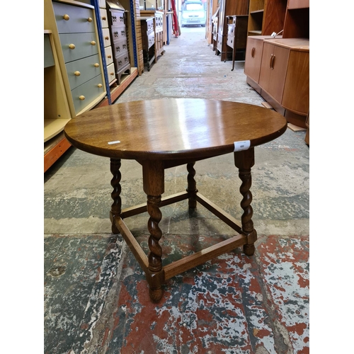 489 - Two items to include an oak circular side table on barley twist supports and a vintage walnut sewing... 