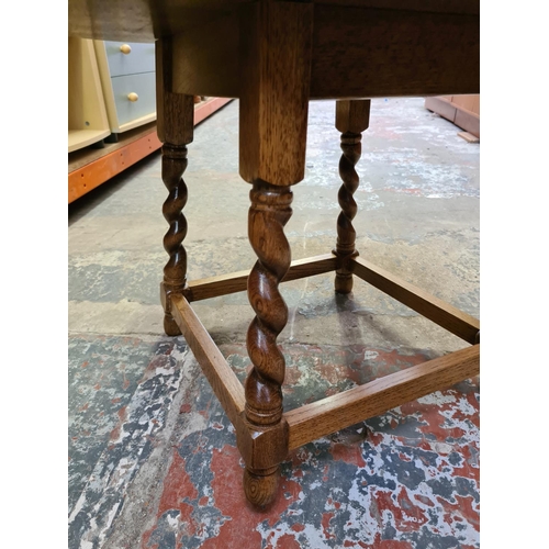 489 - Two items to include an oak circular side table on barley twist supports and a vintage walnut sewing... 