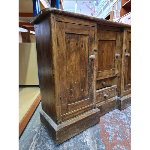 498 - A Victorian pine sideboard with two outer cupboard doors, one central door and two lower drawers