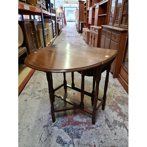 502 - An oak drop leaf gate legged oval occasional table