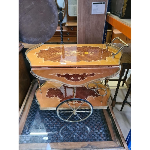 541 - An Italian style mahogany and satinwood effect two tier drinks trolley with brass galleried top