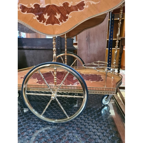 541 - An Italian style mahogany and satinwood effect two tier drinks trolley with brass galleried top