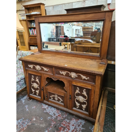 543 - An early 20th century heavily carved oak mirror backed sideboard with rectangular bevel edged mirror... 