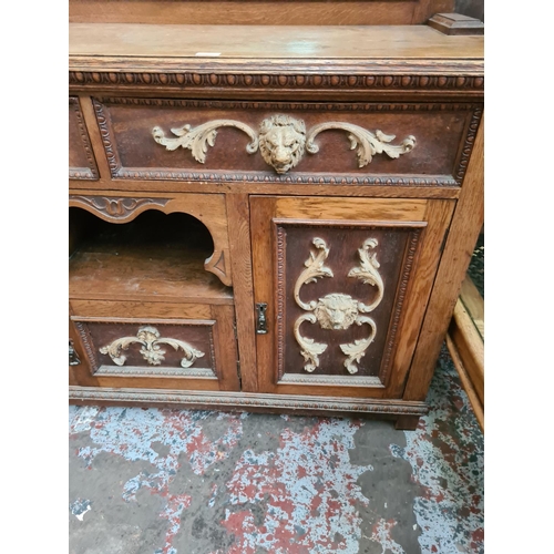 543 - An early 20th century heavily carved oak mirror backed sideboard with rectangular bevel edged mirror... 