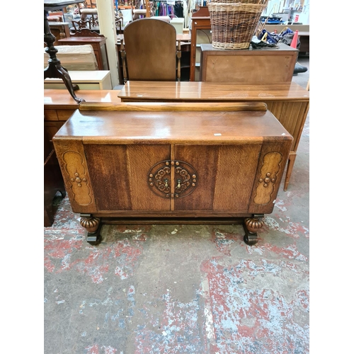 551 - An Art Deco oak sideboard on heavily carved baluster supports with two central cupboard doors, one o... 