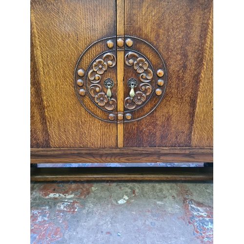 551 - An Art Deco oak sideboard on heavily carved baluster supports with two central cupboard doors, one o... 