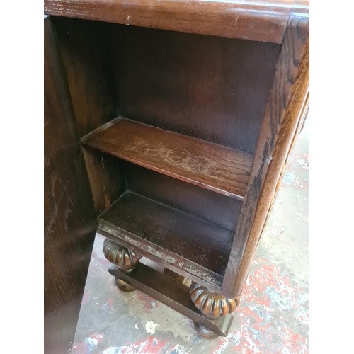 551 - An Art Deco oak sideboard on heavily carved baluster supports with two central cupboard doors, one o... 