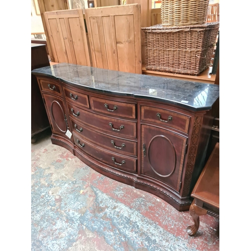 556 - An antique style mahogany serpentine sideboard with solid black marble top, seven drawers and two ou... 