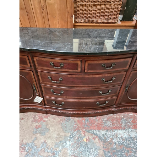 556 - An antique style mahogany serpentine sideboard with solid black marble top, seven drawers and two ou... 