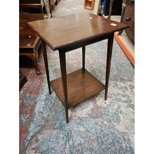 557 - Two items to include an Edwardian oak two tier side table and a modern black painted half moon conso... 