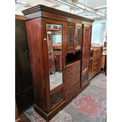 565 - An Edwardian mahogany compactum wardrobe with two bevel edged mirror doors, two upper cupboard doors... 