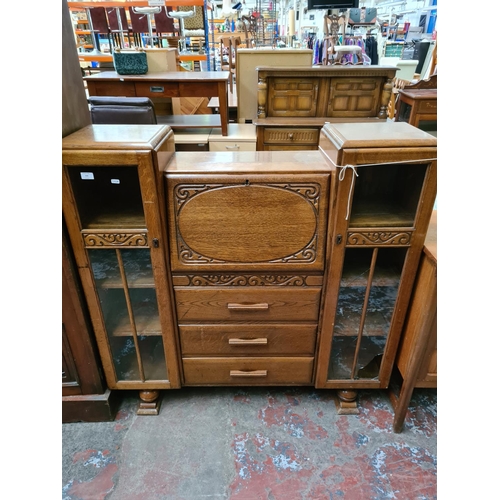 566 - An Art Deco oak side by side bureau bookcase with three central drawers, fall front and two glazed d... 