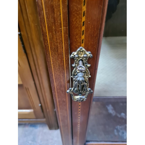 597 - An Edwardian inlaid mahogany display cabinet on tapering supports with one glazed door and key