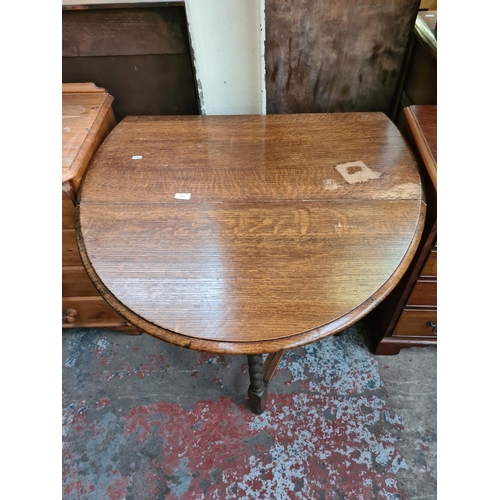 609 - An oak drop leaf gate leg oval dining table on barley twist supports (see condition report)