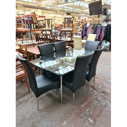 635a - A modern glass dining table on chrome supports with six matching black leatherette dining chairs - m... 