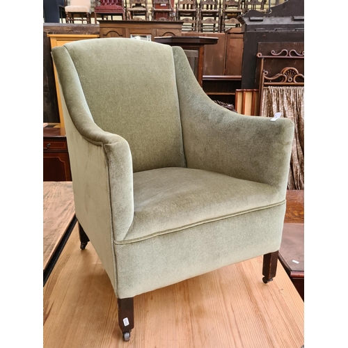 649 - An Edwardian green upholstered armchair on casters