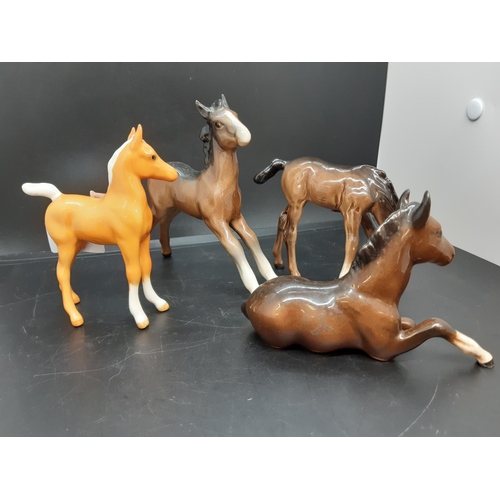 93 - Four Beswick foal figurines to include brown lying foal, palomino foal, head down foal and stretched... 