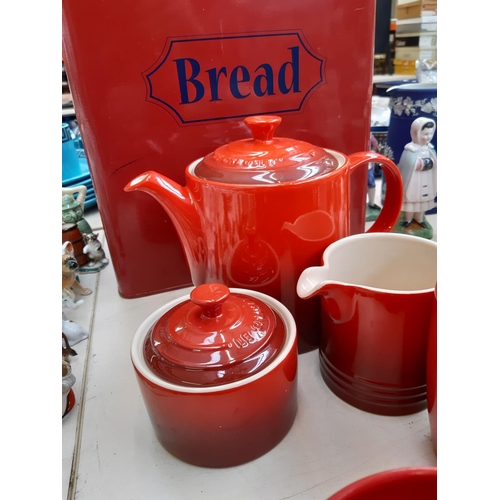 215 - An assortment of red kitchenalia to include a three piece Le Crueuset tea set, set of seven Ethos te... 