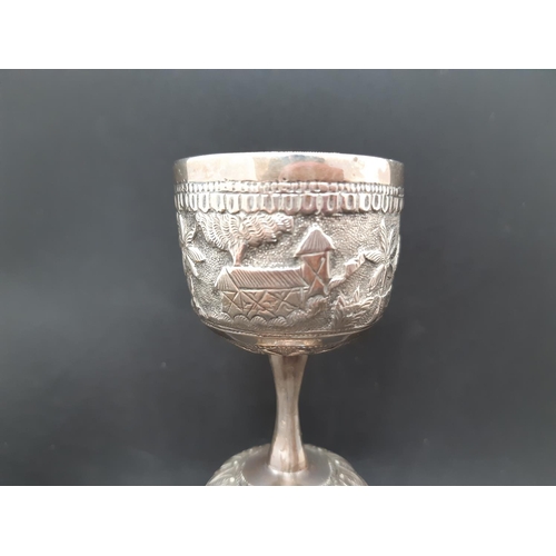 7 - A middle eastern white metal two section goblet with  repousse farming and village scenes - measurin... 