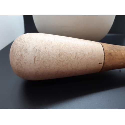 126 - A large porcelain mortar and two wooden handled pestles - mortar measuring approx. 18cm in diameter