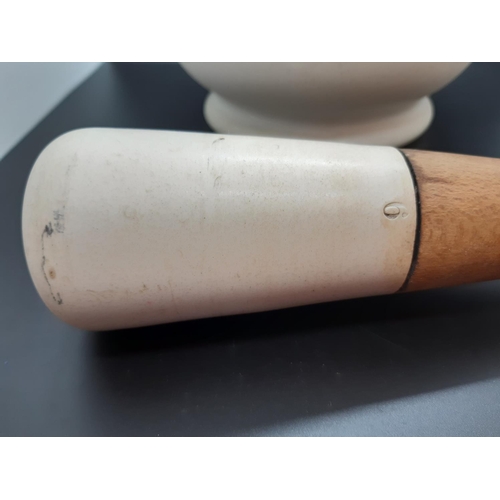 126 - A large porcelain mortar and two wooden handled pestles - mortar measuring approx. 18cm in diameter