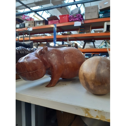 249 - Four pieces of treenware to include carved teak hippo and three carved teak eggs