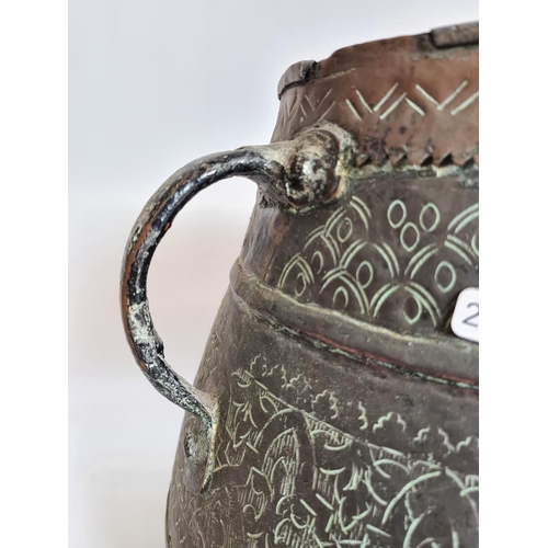 103 - A Middle Eastern hand engraved copper twin handled cauldron - approx. 29cm high