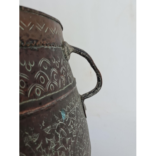 103 - A Middle Eastern hand engraved copper twin handled cauldron - approx. 29cm high