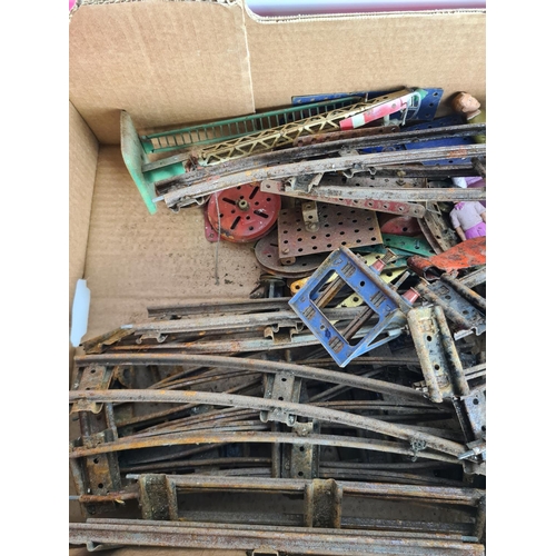 133 - A box containing Meccano and tin plated model railway accessories to include track, tankers, locomot... 