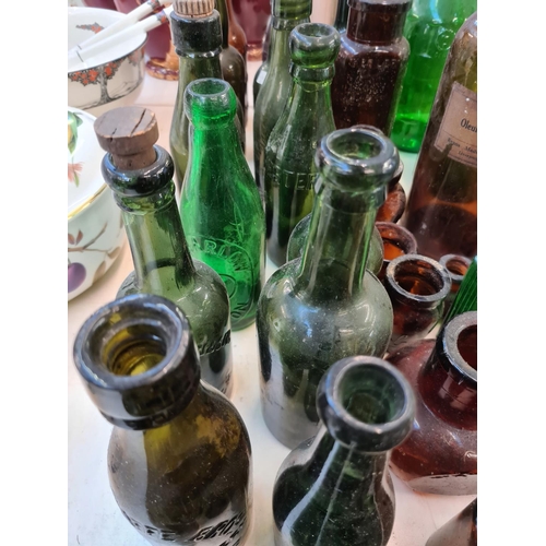 142 - A collection of assorted vintage coloured glass bottles to include Evans Oleum Olivae, Robert Browns... 