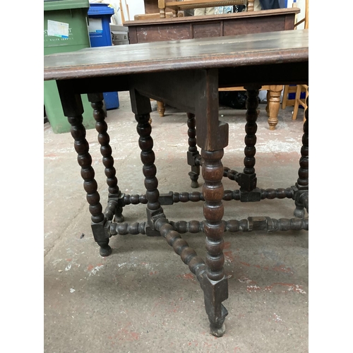 470 - An 18th century oak drop leaf gate leg dining table on barley twist supports