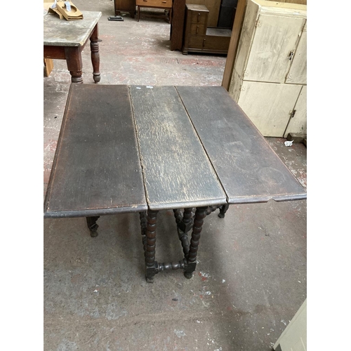 470 - An 18th century oak drop leaf gate leg dining table on barley twist supports