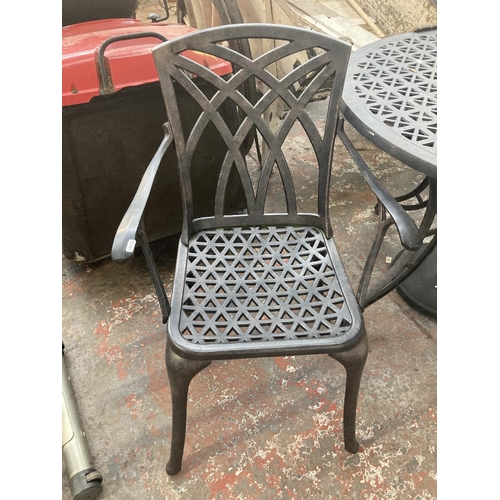 1127 - A four piece cast aluminium patio set comprising circular ornate table, two matching chairs, parasol... 