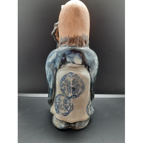 73 - An oriental ceramic figurine of a Chinese elder with impressed character mark to base - approx. 23cm... 