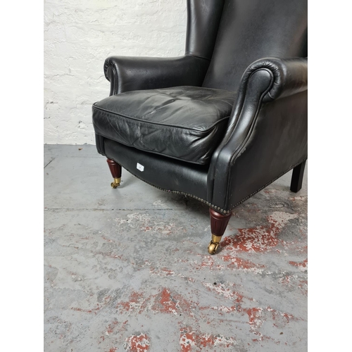 409 - An antique style black leather wing back arm chair