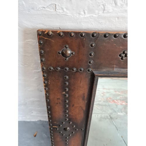 424 - An Arts and Crafts brass studded leather two section stick stand with carved oak centre panel and ma... 