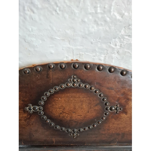 424 - An Arts and Crafts brass studded leather two section stick stand with carved oak centre panel and ma... 