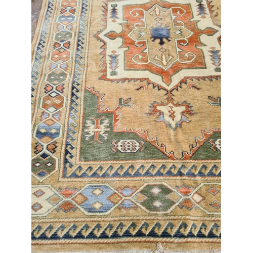 443 - A large vintage tasseled rug in brown, green and orange tones