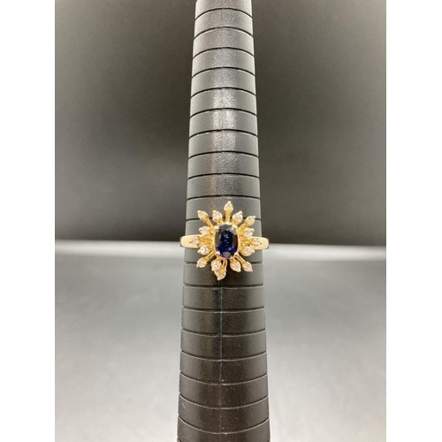 91 - An unmarked gold sapphire and diamond ladies ring with one central sapphire and sixteen surrounding ... 