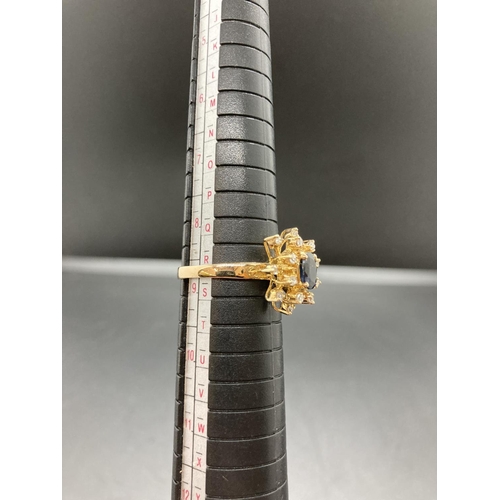 91 - An unmarked gold sapphire and diamond ladies ring with one central sapphire and sixteen surrounding ... 