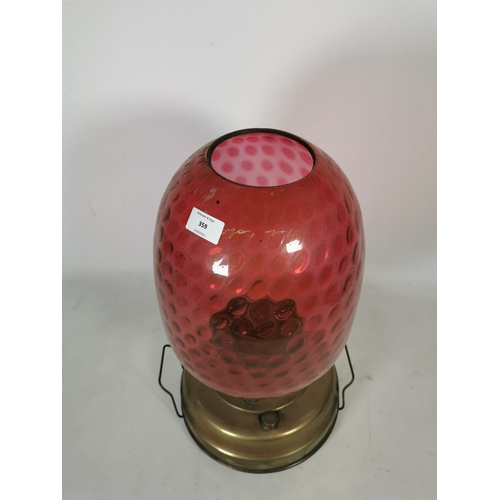 359 - A brass oil lamp with cranberry glass shade - approx. 49cm high