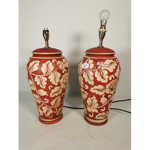 366 - A pair of Aimbry red painted ceramic table lamps with floral design - approx. 44cm high without bulb