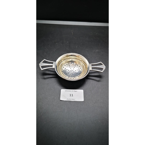 11 - A hallmarked Birmingham silver twin handled tea strainer by 'H&H', dated 1944 - approx. gross weight... 