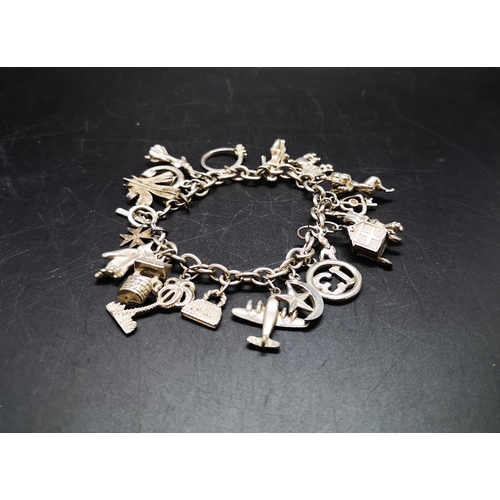 127 - A white metal charm bracelet with various charms - approx. gross weight 52 grams