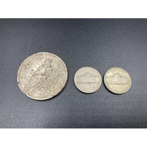 21A - Three American coins, one 90% silver 1922 'Peace' dollar and two 1956 'Jefferson Nickel' five cents