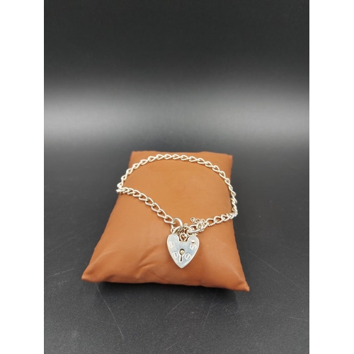 153 - A white metal ladies bracelet with stamped sterling silver heart shaped padlock clasp